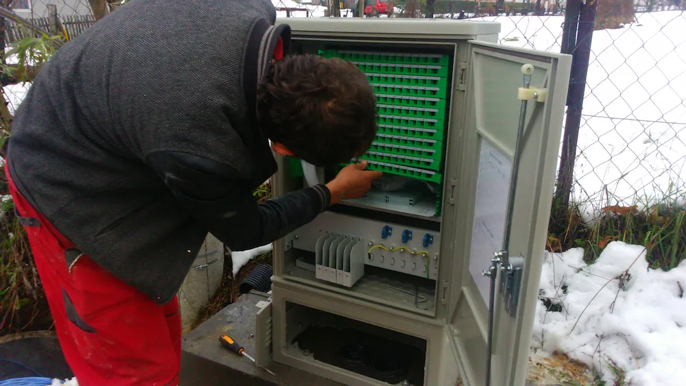 Tehnicar radi na vanjskom optickom ormaru zimi