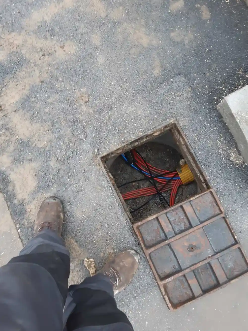 Opticke cijevi u kabelskom oknu na asfaltu