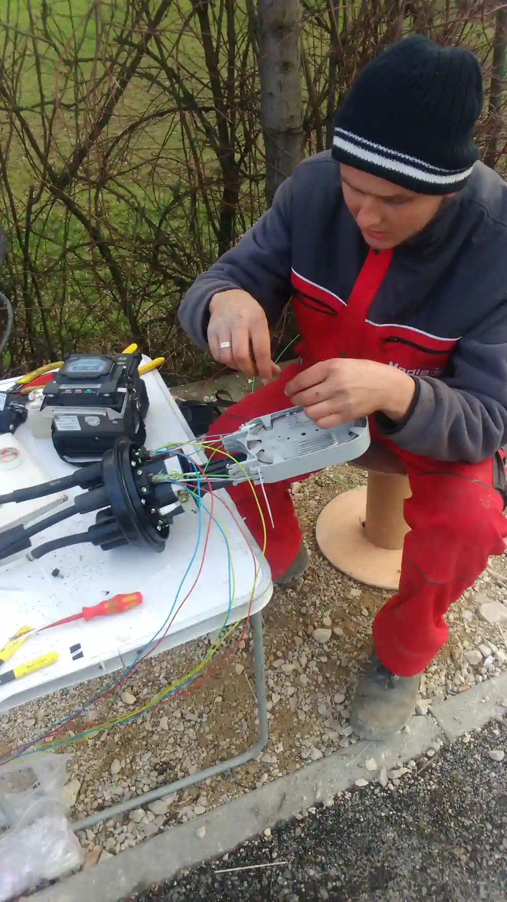 Tehnicar splajsuje opticke kablove na terenu